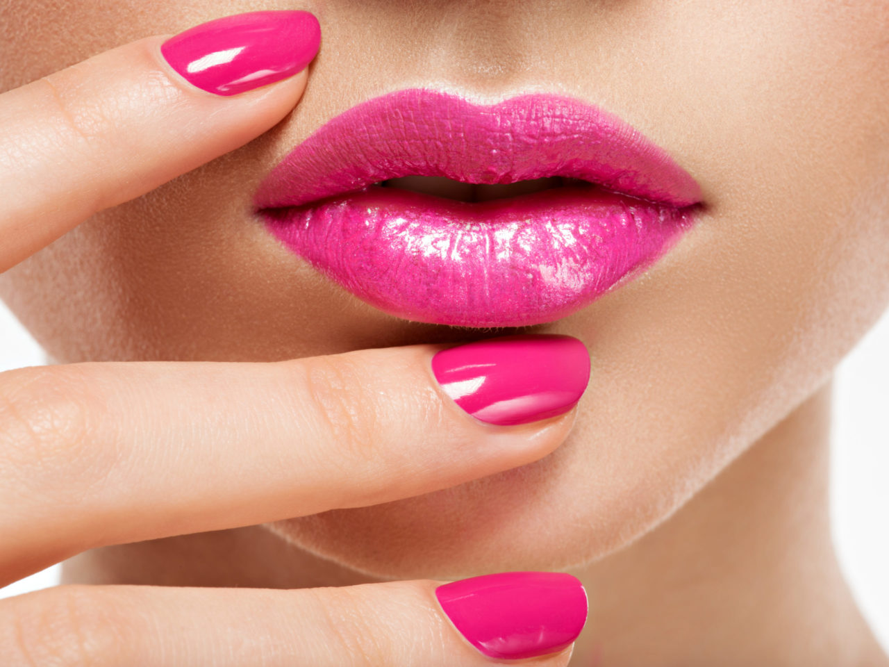 Closeup woman hand with pink nails near lips.
